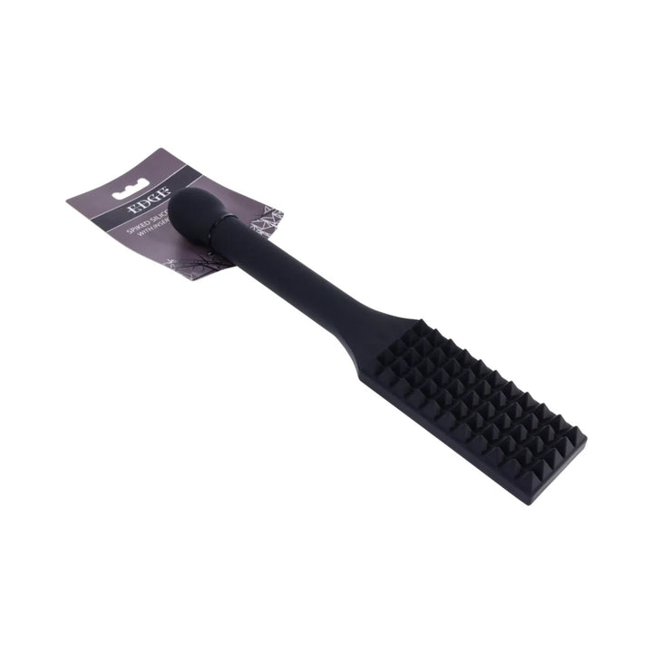Black silicone paddle with rows of raised spikes across the head and a long reinforced handle