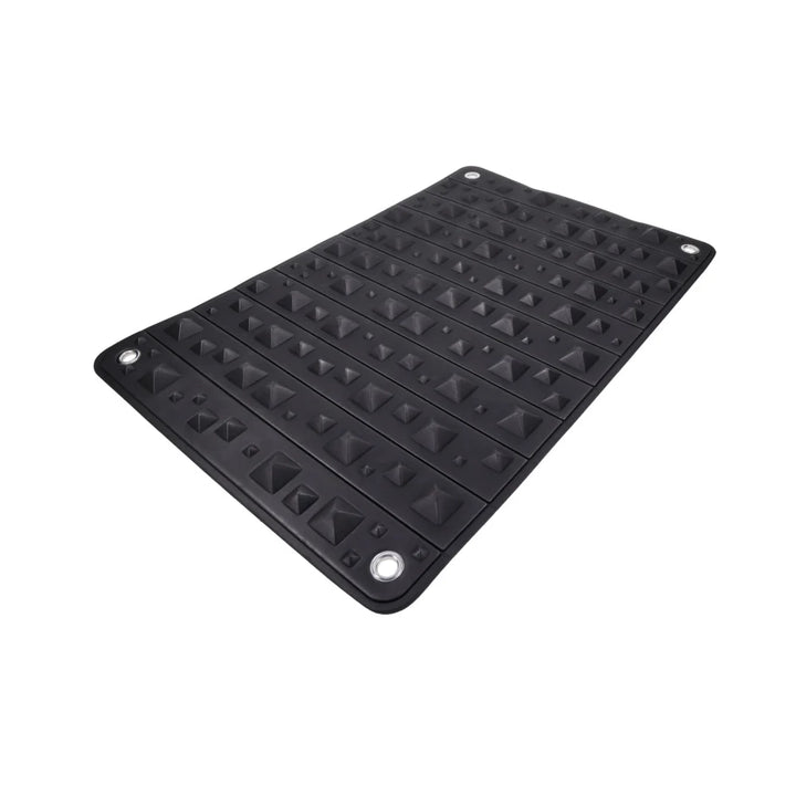 Black foam mat covered in pyramid spikes, shown rolled into its buckled faux leather holster